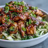 Colorful Egg Roll Bowls with Chicken and Cabbage topped with scallions and sesame seeds are served warm alongside chopsticks.