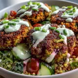 Crispy baked falafel sits atop fluffy quinoa with cucumber and tomatoes in a vibrant Falafel Quinoa Salad Bowl.
