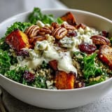 A fresh Harvest Kale Quinoa Bowl ready to eat, featuring massaged kale, blue cheese crumbles, and a drizzle of creamy lemon tahini dressing.