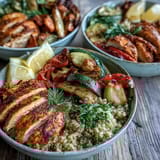 Colorful roasted vegetables and paprika herb chicken over quinoa are drizzled with rose harissa and topped with creamy Greek yogurt.