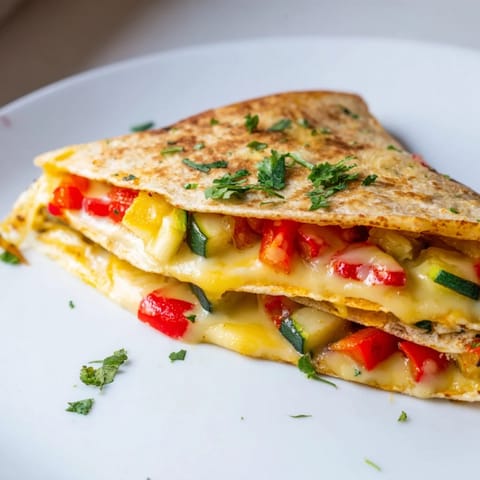 Golden brown quesadilla wedges with melted cheese, sautéed peppers, and onions, ready to dip in cool sour cream.