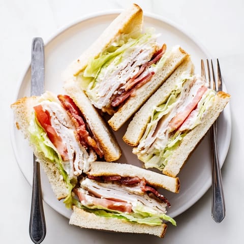 Freshly prepared Turkey Club Sandwich cut into quarters, revealing layers of turkey, bacon, and juicy tomato slices with creamy mayonnaise.