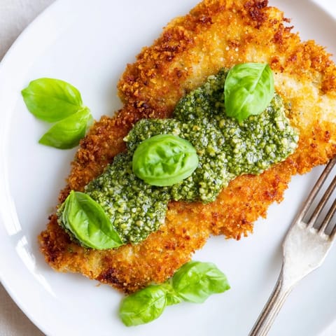 A close-up view of Crispy Pesto Chicken Cutlets with juicy meat and crunchy Parmesan breadcrumbs.