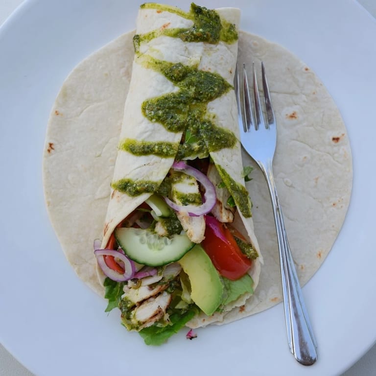 Colorful, herbaceous chimichurri chicken salad wrap ready to serve, garnished with extra sauce and fresh parsley leaves.