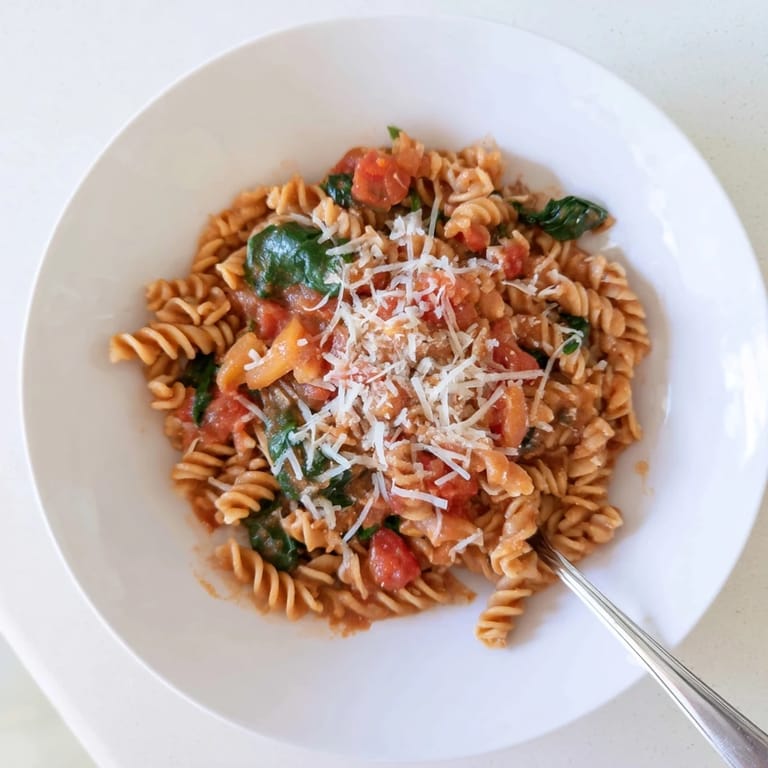 Hearty tomato spinach one-pot rotini with a savory broth base, topped with extra Parmesan cheese.