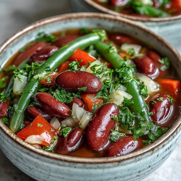 Hearty Three-Bean Salad Soup served hot, featuring red bell peppers and a tangy vinaigrette.