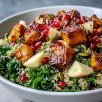 Vibrant Kale Harvest Grain Bowl with roasted sweet potatoes, fluffy quinoa, crisp apple, and juicy pomegranate seeds.