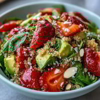 Fresh strawberry avocado quinoa salad with juicy berries, creamy avocado, and zesty citrus dressing in a vibrant bowl.